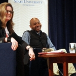 DJ Spooky aka Paul D. Miller smiling while sitting at presentation